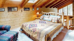 A log cabin bedroom with a bed, a chair, and a skylight. - Serene mountainside cabin, with washer/dryer - near skiing (Almont)
