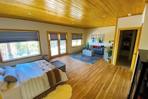 A spacious room with a wooden ceiling, large windows, a bed, a sofa, and a small table. - Spacious dog-friendly cabin with fireplace, mountain view, washer/dryer, & WiFi (Fairplay)
