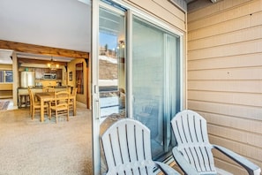 Ein gemütliches Interieur mit Essbereich, einer Küche und einer Glastür, die auf einen Balkon mit Adirondack-Stühlen führt.
