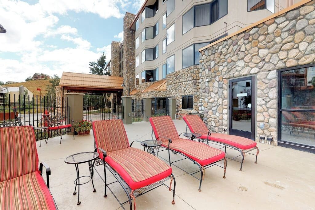 Un hôtel doté d’une terrasse, d’une façade en pierre et de nombreuses fenêtres.