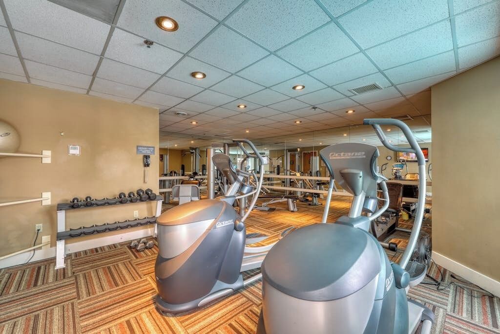 Une salle de sport équipée de machines de cardio, de bancs de musculation et d’haltères.