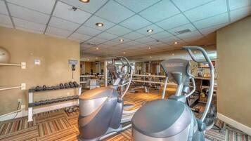 Une salle de sport équipée de machines de cardio, de bancs de musculation et d’haltères.