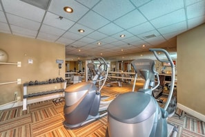 A gym with cardio machines, weight benches, and dumbbells.