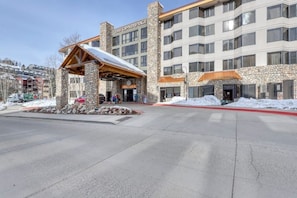 A multi-story hotel with stone facade, a covered entrance, and a snow-covered ground.