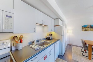 Eine moderne Küche mit weißen Schränken, einem Backofen, einer Kaffeemaschine und einem Spülbecken.