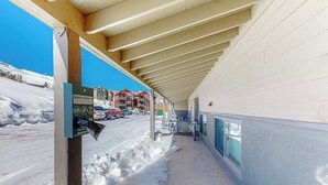A covered walkway with a dog waste station, a view of buildings, and a snow-covered ground. - Mountain-view condo with balcony - walk to ski lifts, near downtown Crested Butte (Crested Butte)