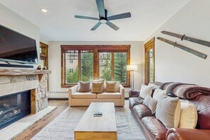 A living room with a fireplace, a sofa, a coffee table, and a television. - Spacious condo w/ full kitchen, shared hot tubs & pool, convenient location (Breckenridge)
