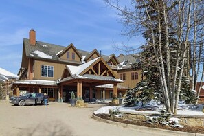 A lodge with a large entrance, a covered porch, and a snow-covered landscape. - Spacious condo w/ full kitchen, shared hot tubs & pool, convenient location (Breckenridge)
