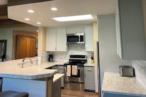 A modern kitchen with white cabinets, a stainless steel microwave, and a built-in oven. - Rustic retreat with slopeside access, mountain views & cozy fireplace (Crested Butte)