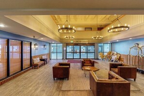 A spacious lobby with a high ceiling, large windows, and multiple seating areas. - Mountain view condo with fireplace & W/D and access to shared hot tub (Crested Butte)