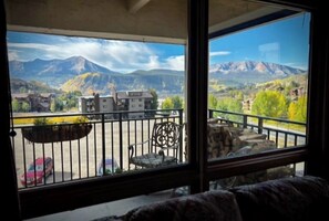 A balcony with a view of mountains, a chair, and a table. - Mountain view condo with fireplace & W/D and access to shared hot tub (Crested Butte)