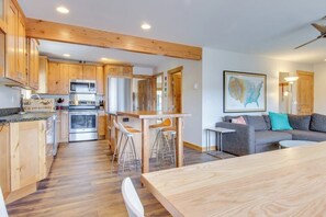 Eine moderne Küche mit Holzausstattung, ein Essbereich mit Tisch und Stühlen sowie ein Wohnzimmer mit Sofa und einer Karte an der Wand.