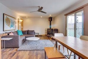 Ein modernes Wohnzimmer mit einer Couch, einem Couchtisch, einem Esstisch, einem Kamin und einem Balkon mit Blick.