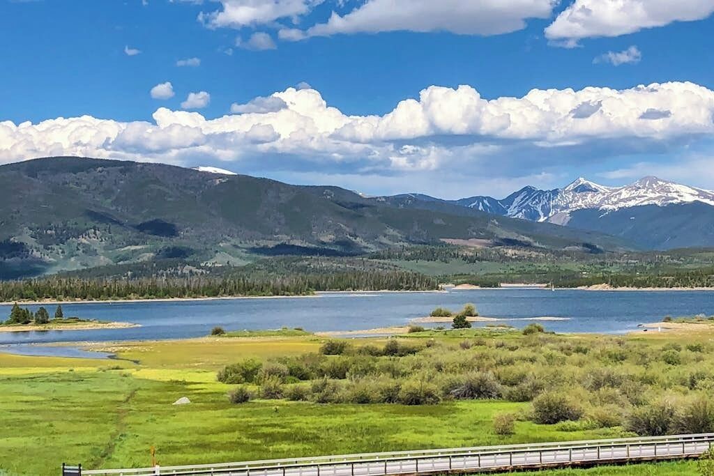 Paisagem pitoresca com montanhas, um lago e uma linha férrea.