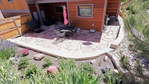 Een houten huis met een terras, buitenmeubels en een pad van stenen.