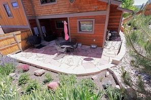 Ein Holzhaus mit Terrasse, Gartenmöbeln und einem Steinweg.