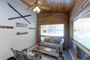 A cozy cabin interior with a sofa, coffee table, and a view of a snowy landscape through large windows. - Mountain View Cabin with Two Private Decks, near Purgatory & Electra Lake (Durango)