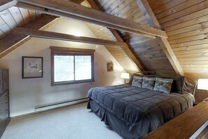 A bedroom with a sloped ceiling, a bed with a dark bedspread, a window, and a framed picture on the wall. - Mountain View Cabin with Two Private Decks, near Purgatory & Electra Lake (Durango)