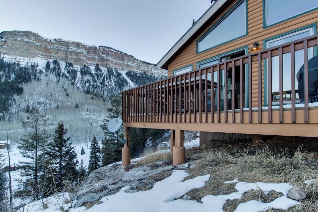 A wooden building with a balcony overlooking a snowy landscape and a lake.