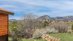 A wooden cabin with a view of mountains and sparse vegetation.