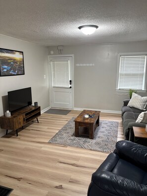 A living room with a TV, sofa, coffee table, and a patterned rug. - 2-bedroom house within walking distance to Northwest Missouri State University (Maryville)