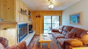 Ein Wohnzimmer mit Kamin, Holzwänden, einer Couch und einem Deckenventilator.