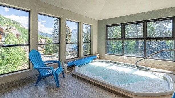 Ein Wellnessbereich mit Whirlpool, großen Fenstern und Bergblick.