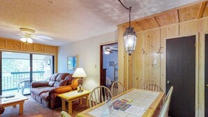 Ein gemütliches Zimmer mit einer Couch, einem Esstisch, Stühlen, einer Lampe und einer Pendelleuchte.