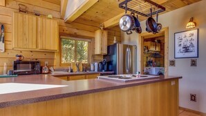 Interior de una cabaña de madera con una cocina que cuenta con una isla grande, un refrigerador y un microondas.