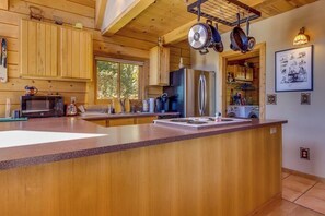 A wooden cabin interior with a kitchen featuring a large island, a refrigerator, and a microwave. - Unplugged dog-friendly getaway with tree-lined views (Durango)