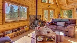 Interior acogedor de una cabaña con paredes de madera, una chimenea de piedra, un sofá y una mesa de centro.