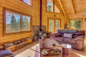 A cozy cabin interior with wooden walls, a stone fireplace, a sofa, and a coffee table. - Unplugged dog-friendly getaway with tree-lined views (Durango)