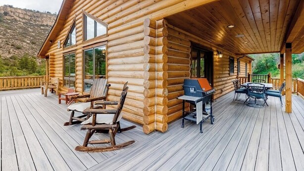A log cabin with a deck, outdoor seating, and a grill. - Secluded home with amazing mountain & lake views, deck, fireplace, & WiFi (Durango)