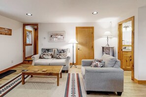 Ein Wohnzimmer mit einer Couch, einem Couchtisch, einer Lampe und einer Tür.