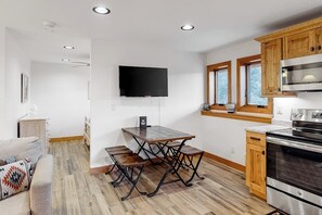 Eine moderne Küche mit Holzschränken, einem Einbauofen und einem flachbildfernseher an der Wand.