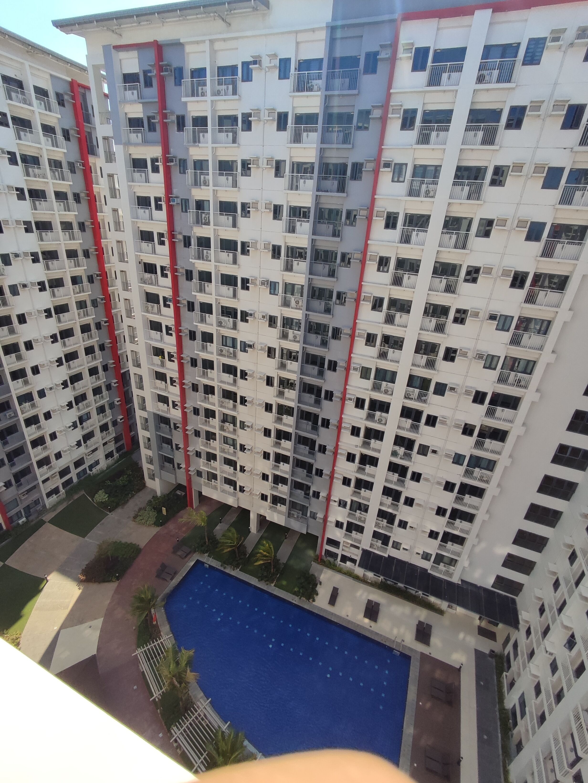 A high-rise residential building with multiple balconies, a central courtyard, and a swimming pool.