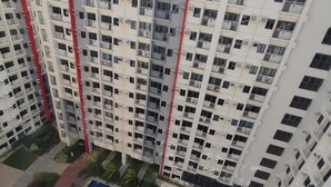 A high-rise building with multiple balconies, a swimming pool, and a red structural feature. - Tower A Cozy 2BR condo in Parañaque w/ AC near NAIA Airport (Parañaque)