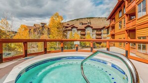 A swimming pool with a wooden deck and a view of a lodge with multiple balconies. - Ski-In/Ski-Out Modern Condo with Shared Hot Tub & Sauna - Views of the Village (Copper Mountain)