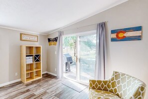 Ein Zimmer mit einer Schiebetür zum Außenbereich, einem hölzernen Bücherregal und einem Sofa mit Giraffenmuster.