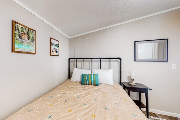 Une chambre à coucher avec un lit, deux tableaux encadrés, une table de chevet et un miroir.