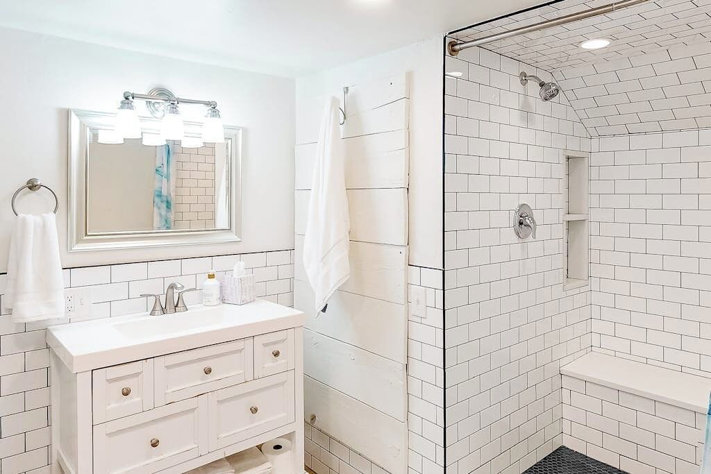 A bathroom with a white sink, mirror, and shower.