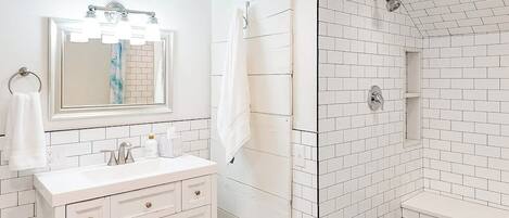 A bathroom with a white sink, mirror, and shower.