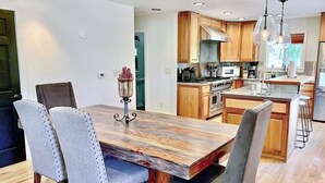 Een moderne keuken met houten kasten, een centraal eiland en een eetgedeelte met een houten tafel en beklede stoelen.