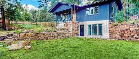 A modern two-story house with a stone foundation, large windows, and a covered porch.