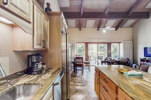 Eine Küche mit Holzschränken, einer Marmorarbeitsplatte und einem Essbereich mit Tisch und Stühlen.