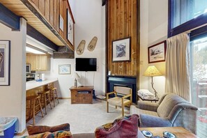 Una sala de estar acogedora con chimenea, televisión y comedor con muebles de madera.