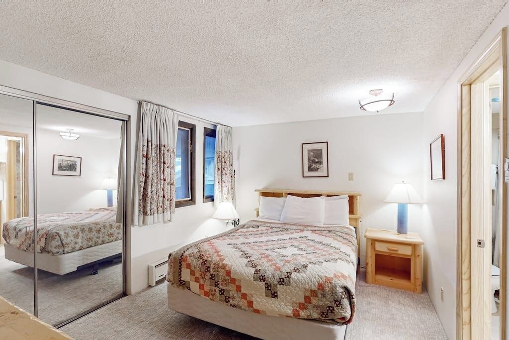 Makuuhuone, jossa on sänky, yöpöytä, peili ja ikkuna, jossa on verhot.