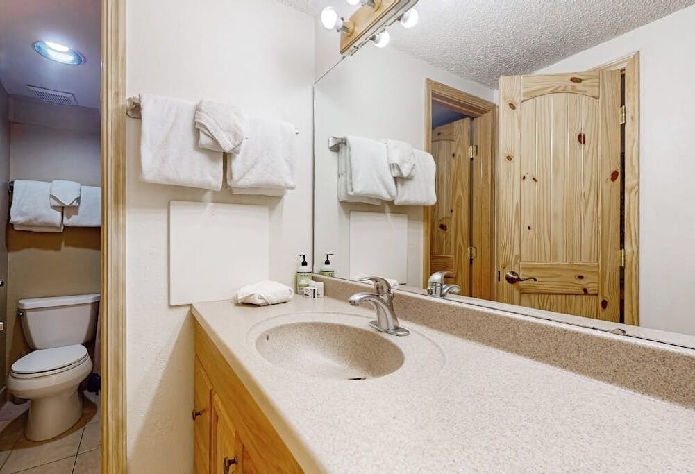 A bathroom with a sink, mirror, and toilet.
