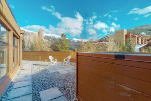 Eine Terrasse mit Holzdeck, zwei weißen Stühlen und einem Whirlpool.