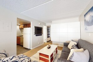 Ein modernes Apartment mit Küche, einem Wohnzimmer mit Sofa und Couchtisch sowie einem großen Fenster.